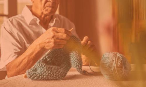 an older man knitting.